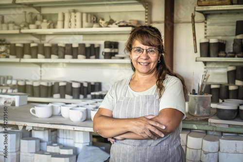 Fotografie Adult woman potter smiling and looking at camera in her studio.
