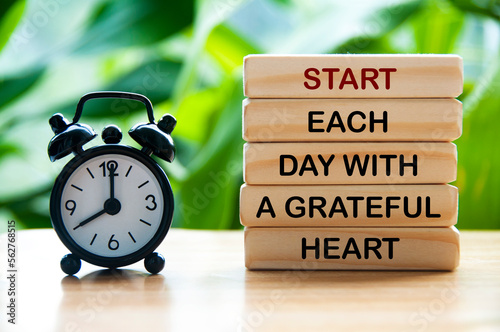 Start each day with a grateful heart text on wooden blocks with alarm clock and nature background. Motivational concept