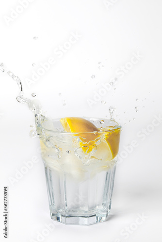Glass of lemonade with splashing water on white background with copy space