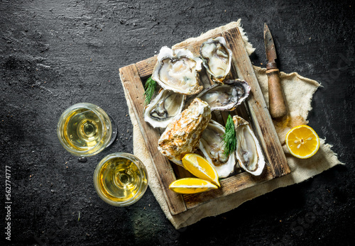 Fotografi Delicious raw oysters with white wine in glasses.