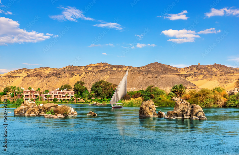 Nile stones and riverbank near Aswan and traditional sailboat, Upper Egypt