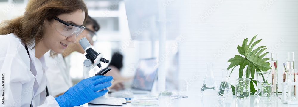 Female scientists researching through microscope doing analysis for ...