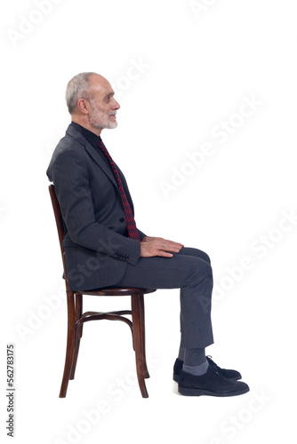 side view of a man sitting on chair with suit and tie looking on white background