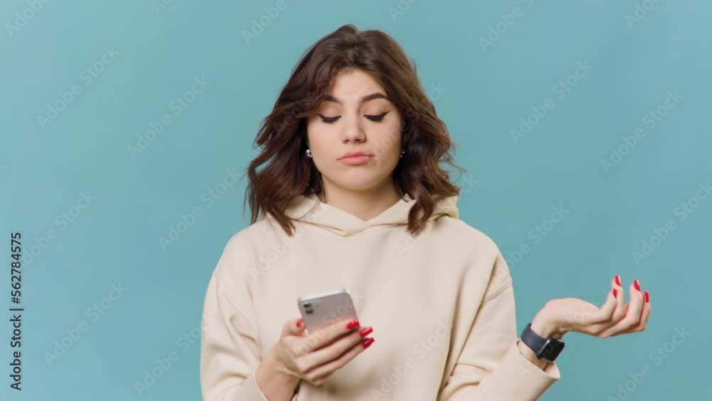 A brunette teenage girl has a perplexed expression as she holds her smartphone and trying A brunette teenage girl has a perplexed expression as she holds her smartphone and trying