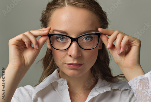 Close up portrait of emotional young woman wearing glasses isolated on grey background.