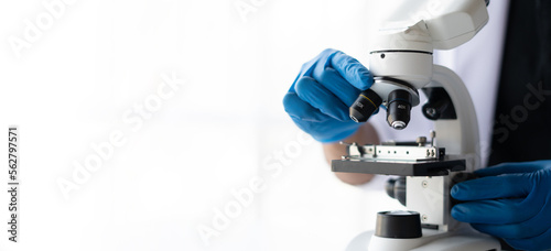 Biological scientist looking at samples by using microscope doing research for new vaccine in pharmaceutical laboratory.