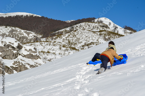 Dos niños con trineos azules en una montaña nevada