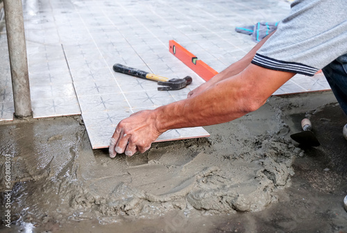 Worker placing ceramic floor tiles on a surface with adhesive mortar, install floor tiles.