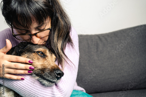Adorable shot of Hispanic young woman kissing ang hugging her dog at home. Copy space on the right side for text