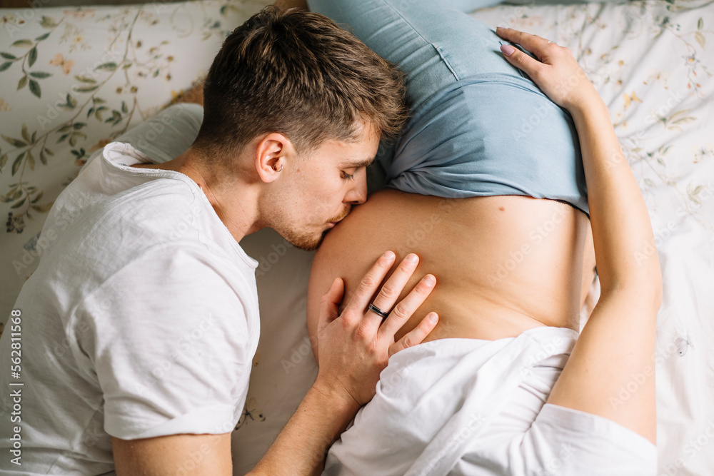 Man kissing pregnant belly of crop woman Man kissing pregnant belly of crop woman