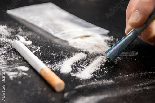 Drug Addiction: Close-up of person using a 20 euro note to snort cocaine on a black table