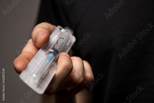 Close-up of a drug dealer hand passing you a heroin syringe. Heroine addiction concept