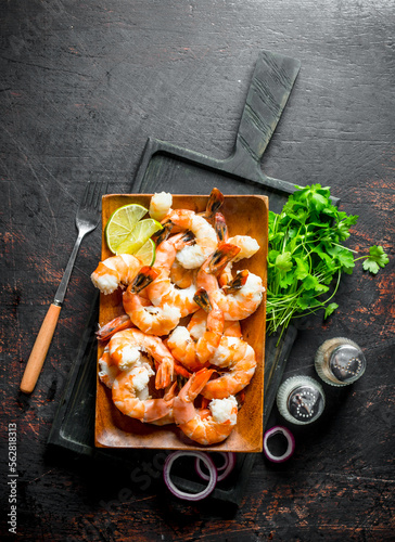 Shrimps on a cutting Board with parsley, spices and lime.
