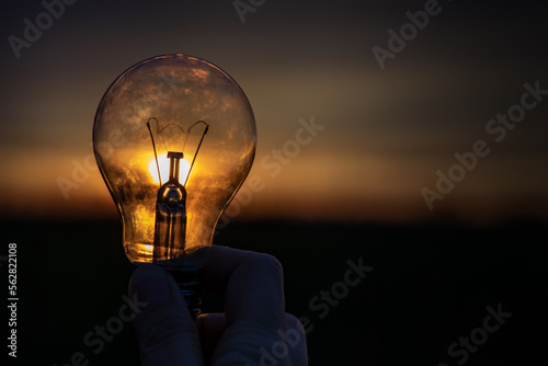 holding lightbulb with sunlight shine through the glass