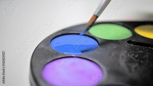 Close up view of watercolor paints. Drawing with paints on paper in kindergarten or home hobies, close-up view of how take color with brush or dip brush into palette of colors. photo