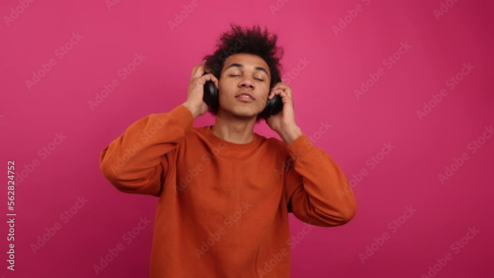 Close-up view of trendy millennial guy streaming music. Portrait of African American man in his 20s using black headphones. High quality 4k footage Close-up view of trendy millennial guy streaming music. Portrait of African American man in his 20s using black headphones. High quality 4k footage
