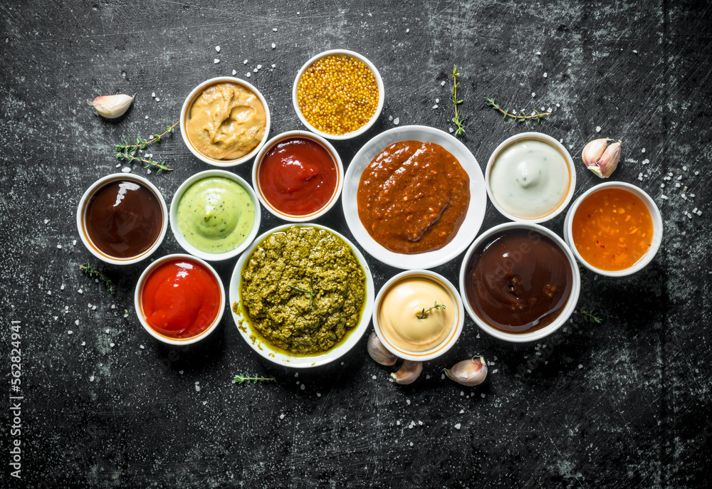 Pesto sauce, guacomole, ketchup, mustard, barbecue sauce in bowls. Pesto sauce, guacomole, ketchup, mustard, barbecue sauce in bowls.