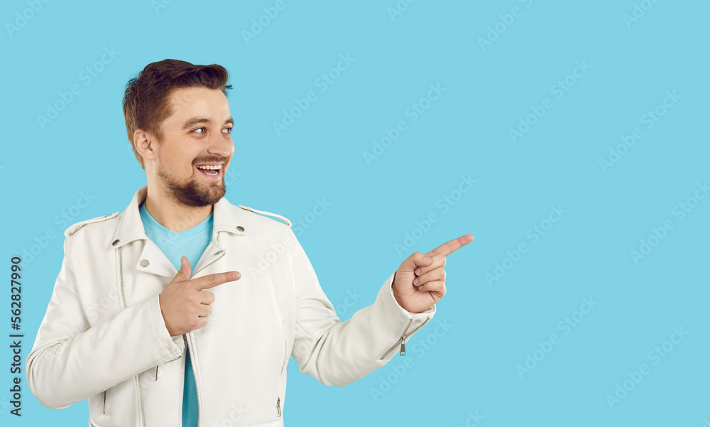 Cheerful man recommend good offer or promotion deal pointing to empty space on bright light blue background. Caucasian man in white jacket is looking at place he is pointing to with both hands. Banner Cheerful man recommend good offer or promotion deal pointing to empty space on bright light blue background. Caucasian man in white jacket is looking at place he is pointing to with both hands. Banner