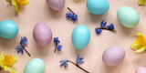 easter background with painted eggs and spring flowers on a pink backdrop, holiday banner.