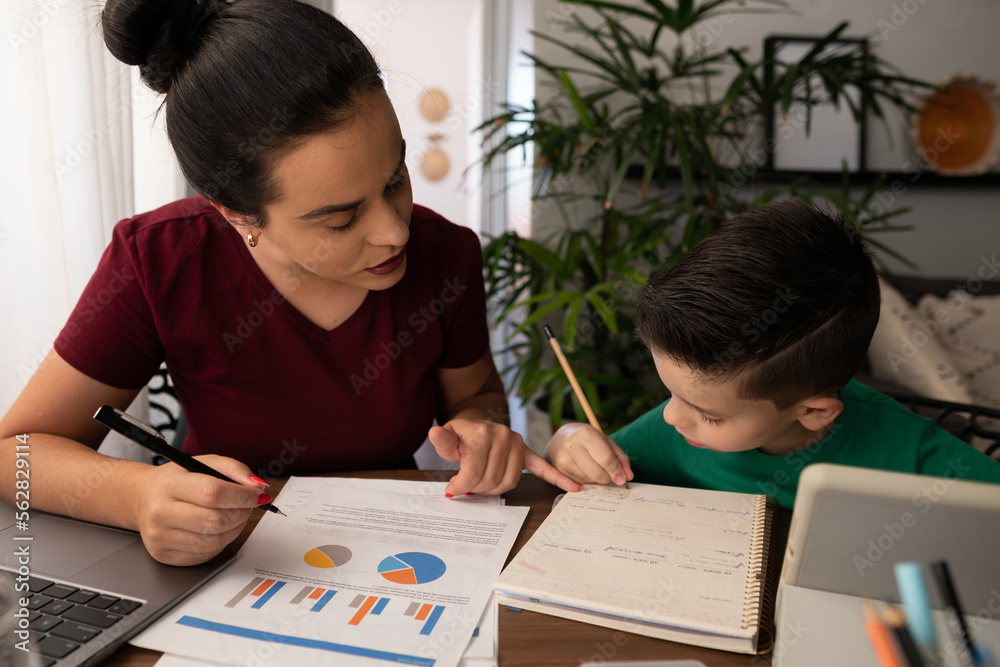 Doting mother and son work and study together at the table in the living room at home Doting mother and son work and study together at the table in the living room at home