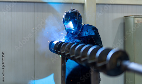 Welding specialist working with protective mask. Factory metal worker welding.