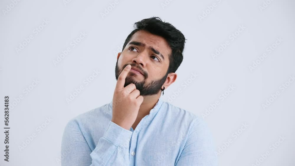Sad Indian man with piercing wearing blue shirt thinking about something in the grey studio Sad Indian man with piercing wearing blue shirt thinking about something in the grey studio