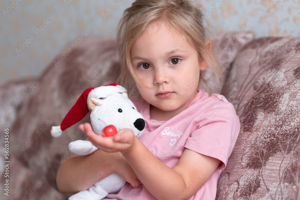 A girl of four years old sits with her inrushka, a white bear and an apple close-up. A girl of four years old sits with her inrushka, a white bear and an apple close-up.