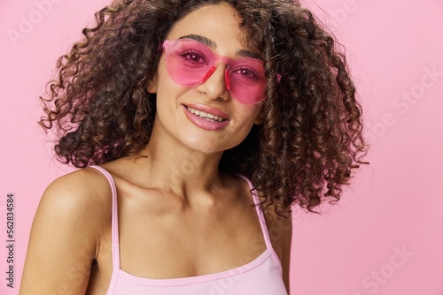 Happy woman afro curls hair dancing on a pink background in summer pink t-shirt jeans and glasses  summer vibe  copy space