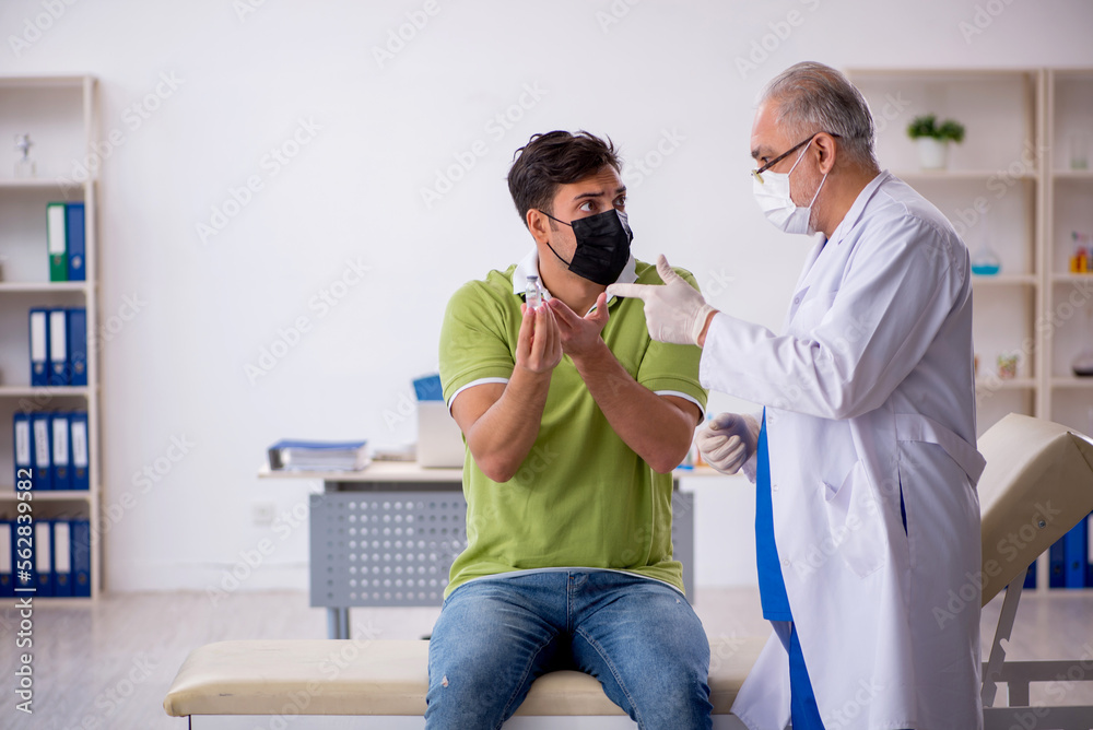Young male patient visiting old male doctor in vaccination conce Young male patient visiting old male doctor in vaccination conce