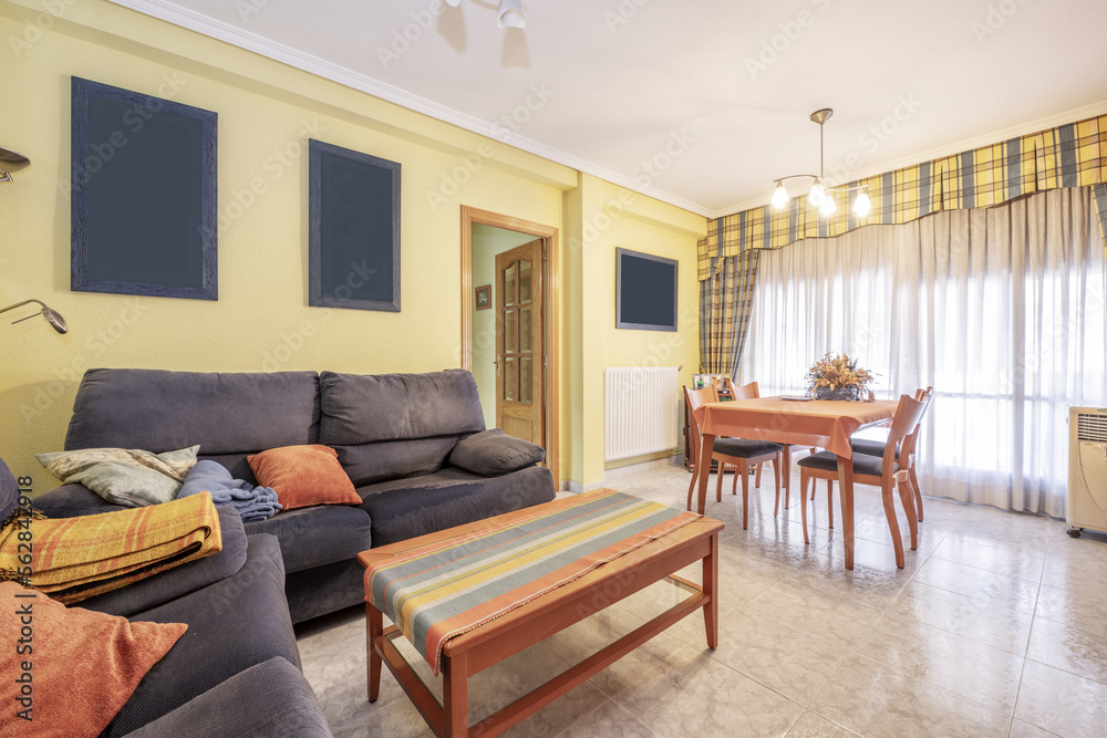 Fototapeta premium Living room of a house with blue fabric armchairs and cherry wood coffee and dining table
