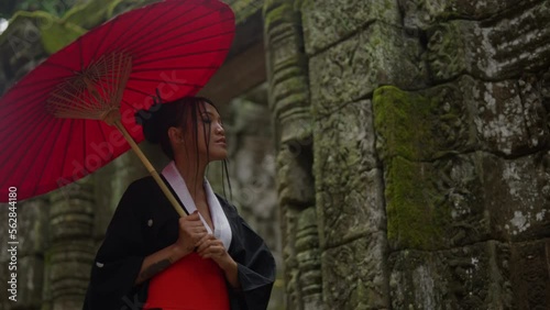 Woman Walking And Looking At Mossy Temple Stone Walls photo