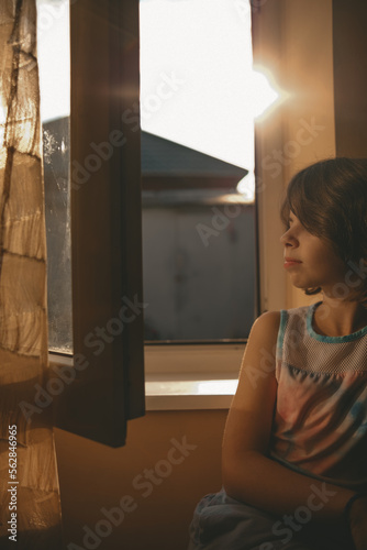 a girl looks out the window on a sunny day