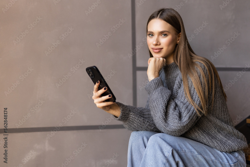 Naklejka premium Shot of an attractive young woman sitting on the stairs and using her cellphone while home