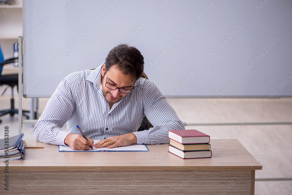 Young male teacher sitting in the classroom Young male teacher sitting in the classroom