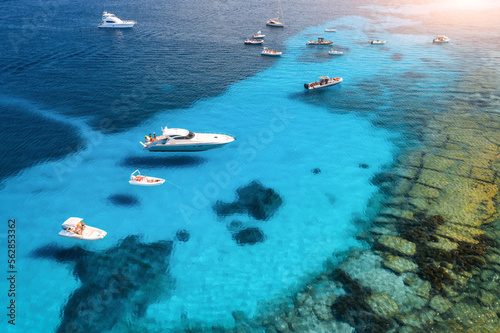 Aerial view of luxury yachts on blue sea at sunset in summer. Sardinia, Italy. View from above of speed boats, yachts, sea lagoon, shore, transparent water. Top view from drone. Tropical seascape