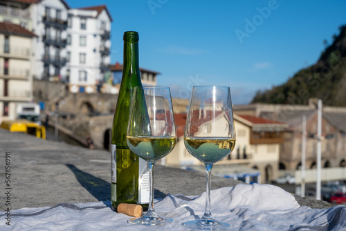 Tasting of txakoli or chacolí slightly sparkling very dry white wine produced in Spanish Basque Country with view on old port and village Getaria, Spain photo