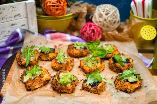 Baked sweet potato bites appetizer with quinoa seeds and ruccola leaves on top