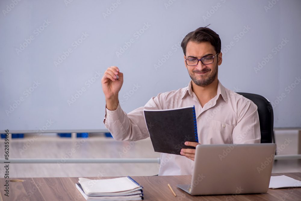 Young male teacher sitting in the classroom Young male teacher sitting in the classroom