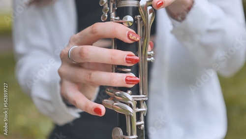 A girl plays the clarinet in the summer in the park. Close-up of her hands. photo