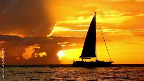 Silhouetted sailboat and dramatic seascape during sunset