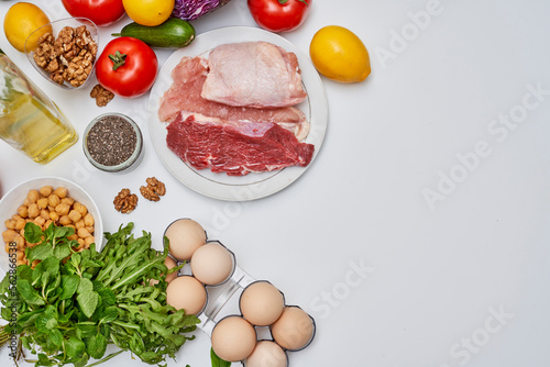 food that includes meat, eggs, vegetables, nuts and other items on a white background with space for text