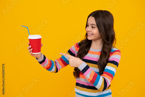 Child girl 12, 13, 14 years old with take away cup of cappuccino coffee or tea. Teenager with takeaway mug on yellow background, morning drink beverage. Happy teenager, positive and smiling