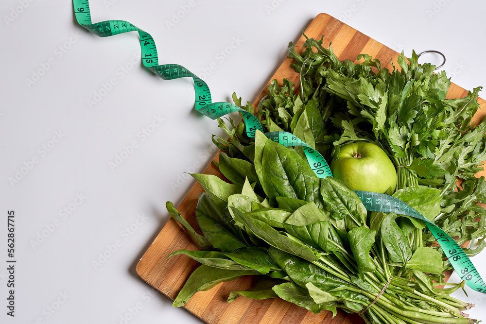some green vegetables on a cutting board with a measuring tape
