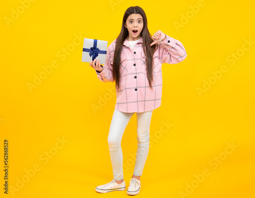Emotional teenager child hold gift on birthday. Funny kid girl holding gift boxes celebrating happy New Year or Christmas. Angry teenager girl, upset and unhappy negative emotion.