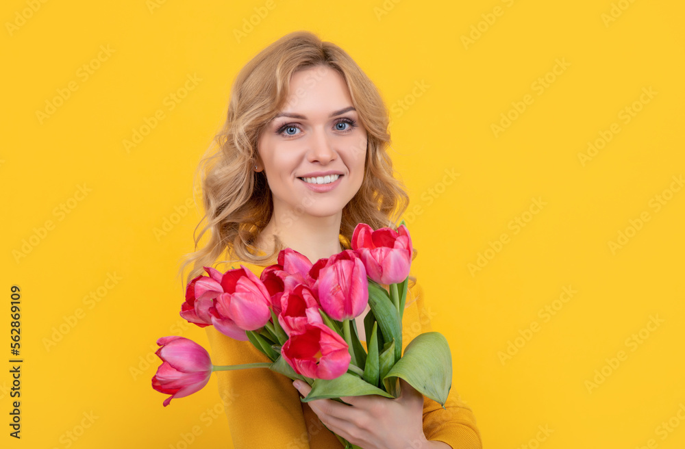 glad young woman with spring tulip flowers on yellow background