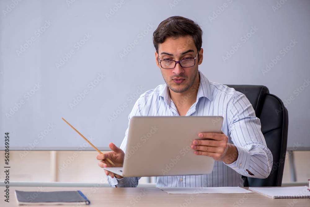 Young male teacher sitting in the classroom