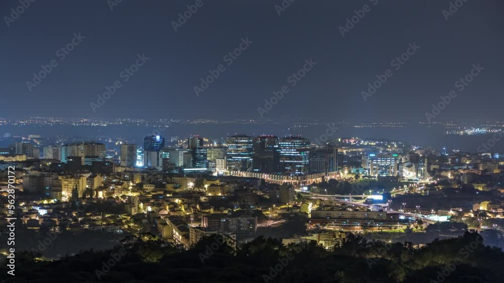 Overview of Lisbon and Almada from a viewpoint in Monsanto night timelapse. Aerial top panorama with traffic on illumitated city streets Overview of Lisbon and Almada from a viewpoint in Monsanto night timelapse. Aerial top panorama with traffic on illumitated city streets