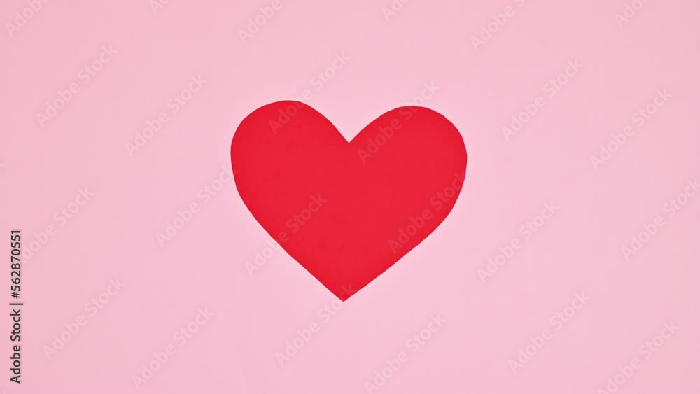 Two pieces of heart connecting in one on pastel pink background. Flat lay. Stop motion Two pieces of heart connecting in one on pastel pink background. Flat lay. Stop motion