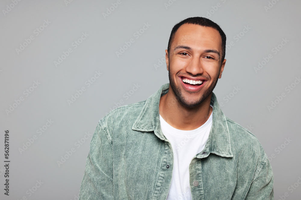 Obraz premium Portrait of smiling African American man on light grey background. Space for text