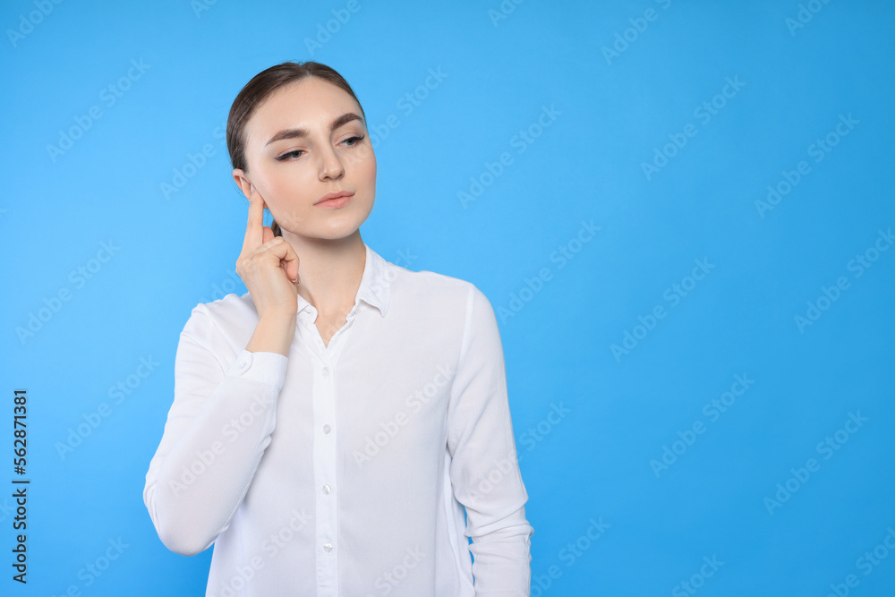 Young woman suffering from ear pain on light blue background. Space for text Young woman suffering from ear pain on light blue background. Space for text